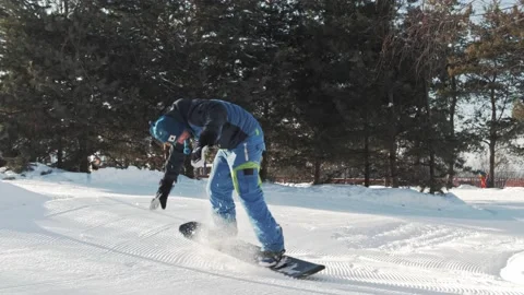 Snowboarder trying to climb the hill performing a penguin walk butter trick 動画素材 221581803