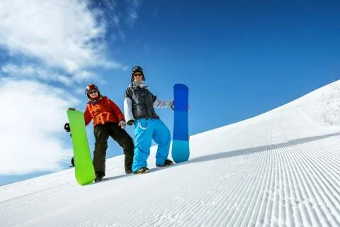Snowboarders posing on blue sky backdrop in snow mountains Stock Photos
