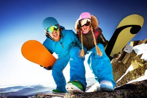 Snowboarders posing on blue sky backdrop in mountains Stock Photos