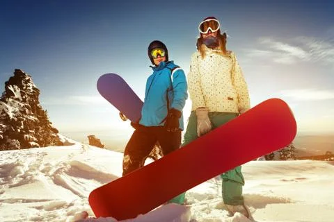Snowboarders posing on blue sky backdrop in mountains Stock Photos