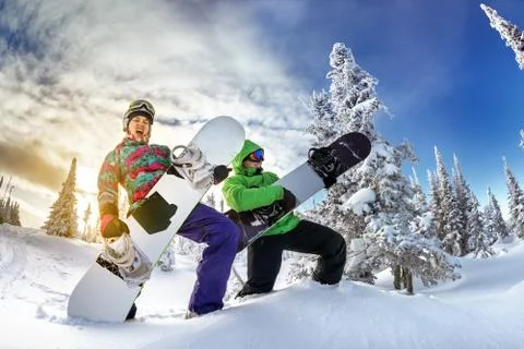 Snowboarders posing on blue sky backdrop in mountains Stock Photos