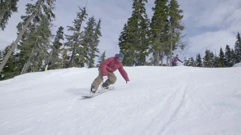 Snowboarders skating down the snow clad mountain slope in slow motion Stock Footage 80026256