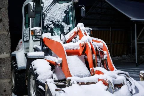 Snowbound Orange Front End Loader Under Corrugated Roof at Barn Foto stock