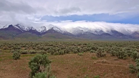 Snowcapped desert mountains and clouds spring Steens Mountain from Alvord Desert Stock-Footage 81877053