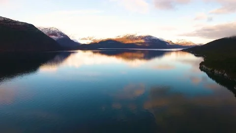 Snowcapped mountains and coniferous trees along the beautiful lake during sunset Stock-Footage 79643997