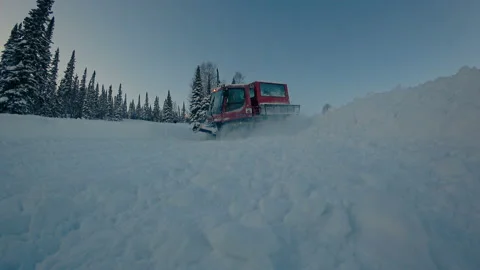 Snowcat rides down the road in the mountain valley Stock Footage 99459257