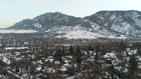Snowed city by mountains - Drone camera moves back through city then down Video stock 138261073