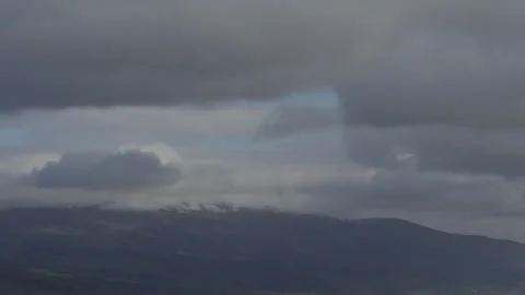 Snowed Peak Of A Mountain Covered With Grey Clouds And Sunlight Dark Forest Vídeos de archivo 331407766