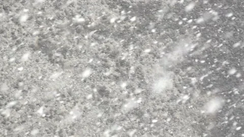 Snowfall against the background of a gray stone wall in winter Stock Footage 91442336