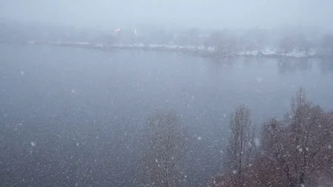 Snowfall on the background of the lake. The snow falls on the trees with fallen Video stock 83341358