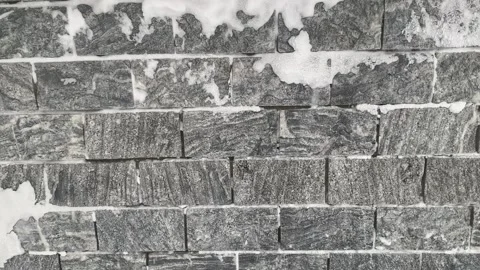 Snowfall on the background of a stone gray wall. Stock Footage 232487756