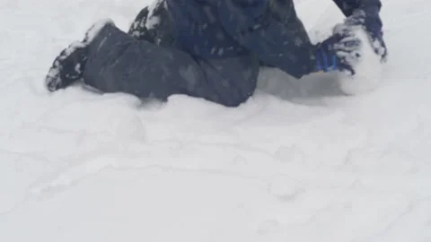 In a snowfall, a child makes a snowball rolling on fresh snow. selective focus. Stock Footage 220615617