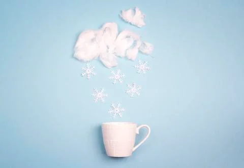 Snowfall in the coffee cup on blue background.  Winter weather concept. Stock Photos
