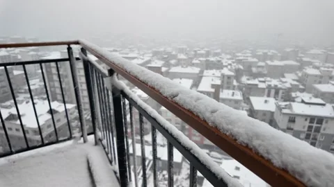 Snowfall covers city rooftops from balcony view creating winter wonderland .. Stock Footage 331719686