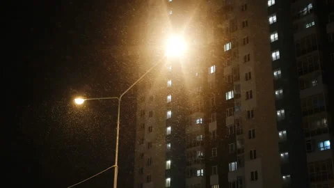 Snowfall in the evening against the background of the windows of an apartment 스톡 동영상 169782116