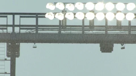 Snowfall in front of illuminated flood lights in stadium Stock Footage 104770901