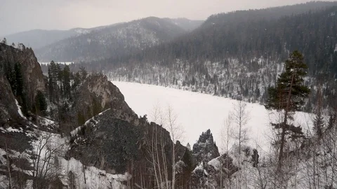 Snowfall in the mountains above the river in winter, view from top Video stock 120698833
