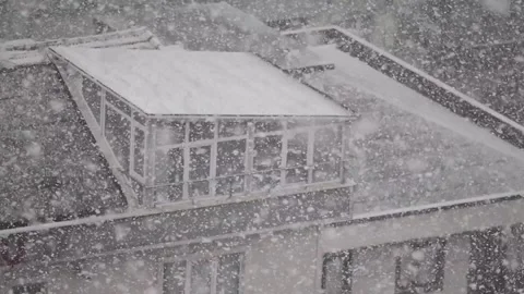 Snowfall over a building rooftop with a dormer window, heavy winter weather. Vídeo Stock 332407407
