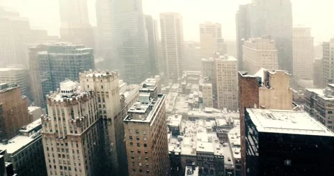 Snowfall Over a Modern Cityscape Seen from Office Window Видео 323681601
