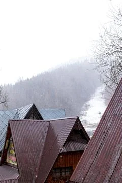 Snowfall Over Mountain Cabins with Forest Hills in Background Foto stock