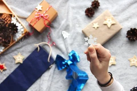 Snowflake in hands. Gift wrapping process. Blue bow. Gifts in craft paper Stock Photos