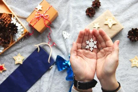 Snowflake in hands. Gift wrapping process. Blue bow. Gifts in craft paper Stock Photos