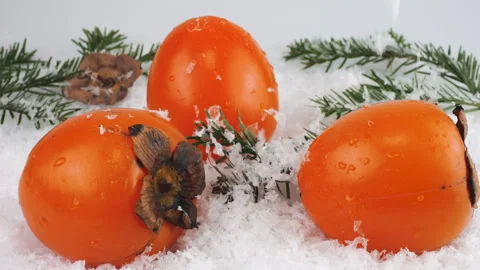 Snowflakes fall on fresh ripe persimmon fruits against a background of snow. Stock-Footage 297929573