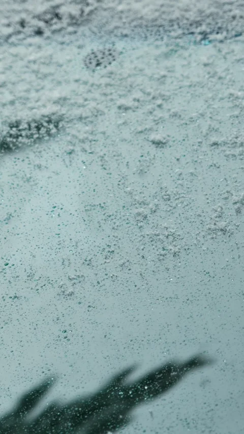 Snowflakes fall on the windshield of a car on a snowy winter day. Snowy weather. Stock Footage 329923944