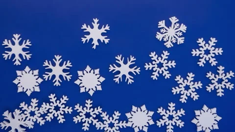 Snowflakes falling on blue background, stop motion animation, 4K Stock Footage 141428897