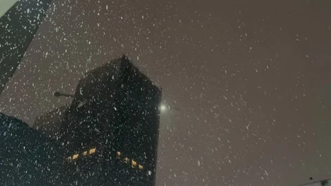 Snowflakes Falling at Night in Front of Dark Buildings and Lit Windows Video stock 328086062