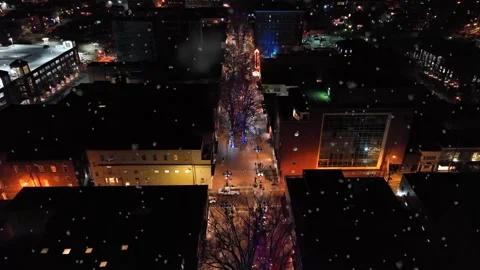 Snowflakes falling from night sky over decorated christmas street. Lighting Stock Footage 299345970