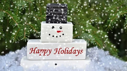 Snowflakes falling on the wooden snowman decorated with Happy Holidays text Stock Footage 116078053
