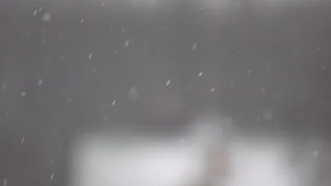 Snowflakes fly in different directions on an unflattering background of roofs of 스톡 동영상 85879992