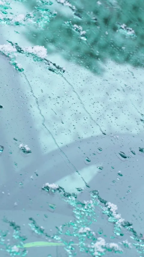 Snowflakes melt on the windshield of the car. Drops of water run down the glass. Stock Footage 313855825
