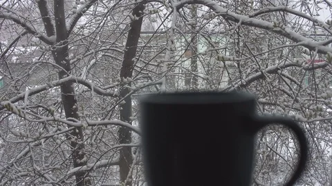 Snowing outside the window and steaming from mug. Stock Footage 108865333