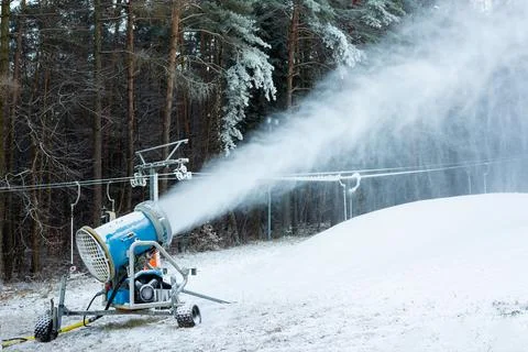 Snowmaking Machine Producing Artificial Snow In Forest Stock Photos