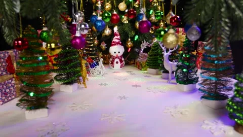 Snowman among small Christmas trees, reindeer and swinging decorations Stock Footage 257672176