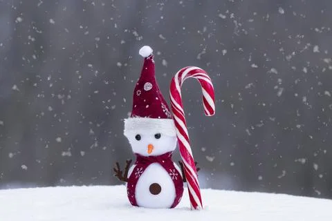 A snowman on a candy cane with a grey background.Winter time. Stock Photos