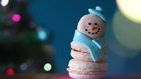 Snowman dessert macaron decorated with hat and scarf against Christmas tree Stock-Footage 255922402