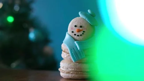 Snowman dessert macaron decorated with hat and scarf with colorful lights and Stock-Footage 255922432