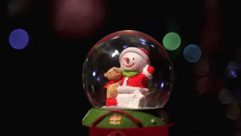 Snowman in a glass ball against the background of blinking blurry lights. snow d Stock Footage 165543653