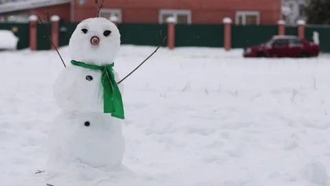 Snowman with green scarf on the background of white snow in winter in the wind Stock Footage 314888341