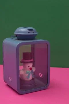 Snowman instead of a candle in a blue lantern on a pink green background. Min Stock Photos