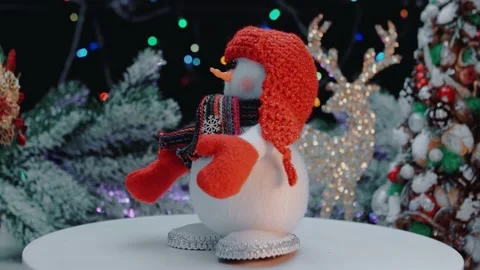 A snowman in a red hat is spinning on the platform, against the background of Stock Footage 145024468