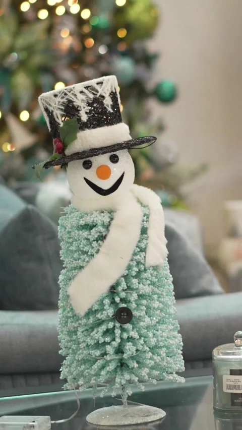 A snowman sits at a table in the decorated living room in front of a Christmas Stockbeeldmateriaal 344631436