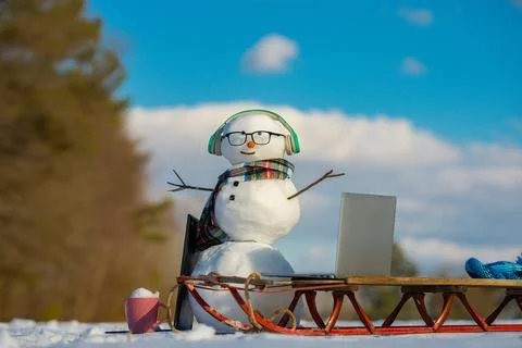 Snowman using laptop outside. Winter online shopping. Snowman programmer Stock Photos