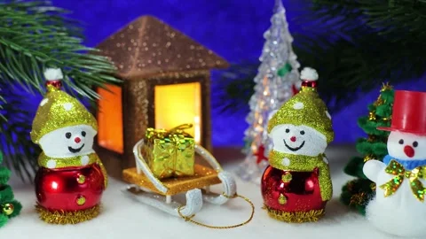 Snowmen and a sled with gift against of Christmas trees and a Christmas lantern Stock Footage 336971151