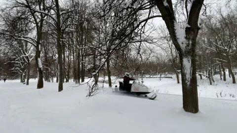 A snowmobile drives in the park in winter Stock Footage 261565393