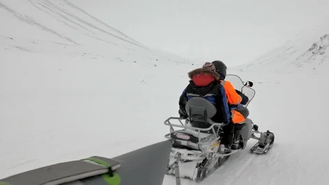 Snowmobile pulls grey snow banana boat with people closeup Video stock 109744396
