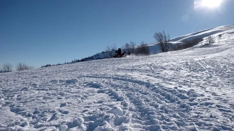 A Snowmobile Rides by With Two Passengers on a Snowed Over Mountain Road at Ski Stock Footage 72192836